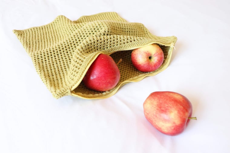 The Crochet Eco-Friendly Fruit & Veggie Bag in green lime with the zipper open showing some apples