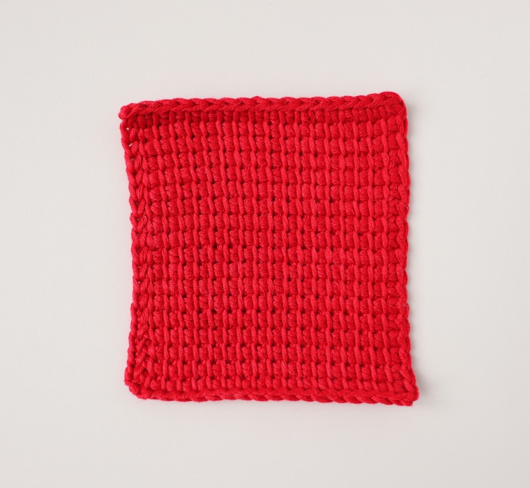 The square red Tunisian crochet piece after blocking
