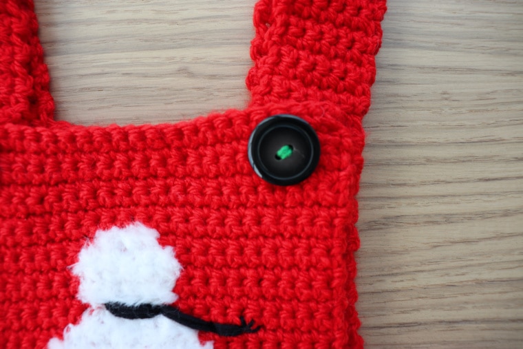 Detail of the button attached with green yarn on the Christmas Baby Over