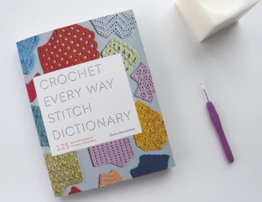 The Crochet Every Way Stitch Dictionary with a crochet hook and a candle
