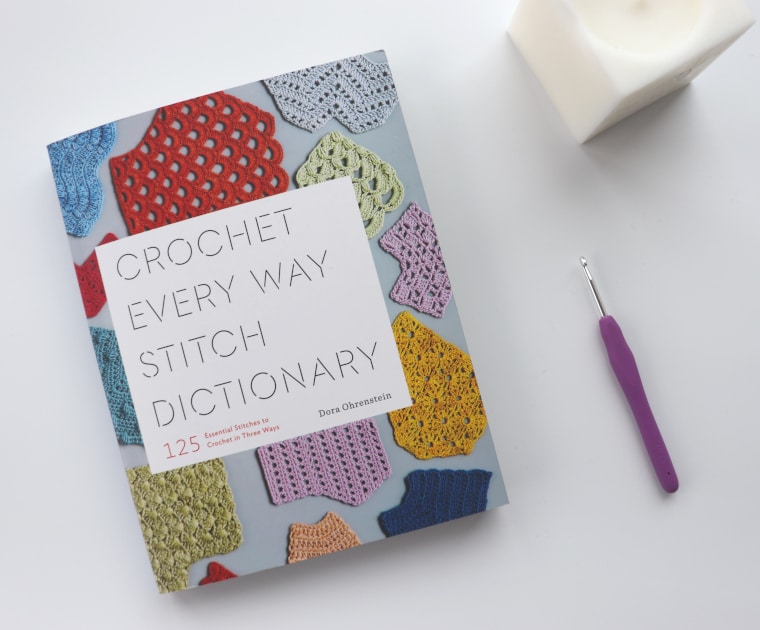 The Crochet Every Way Stitch Dictionary with a crochet hook and a candle