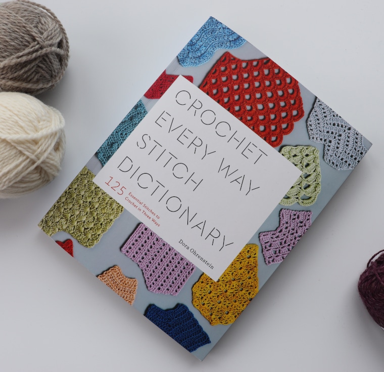 The Crochet Every Way Stitch Dictionary and skeins of yarn