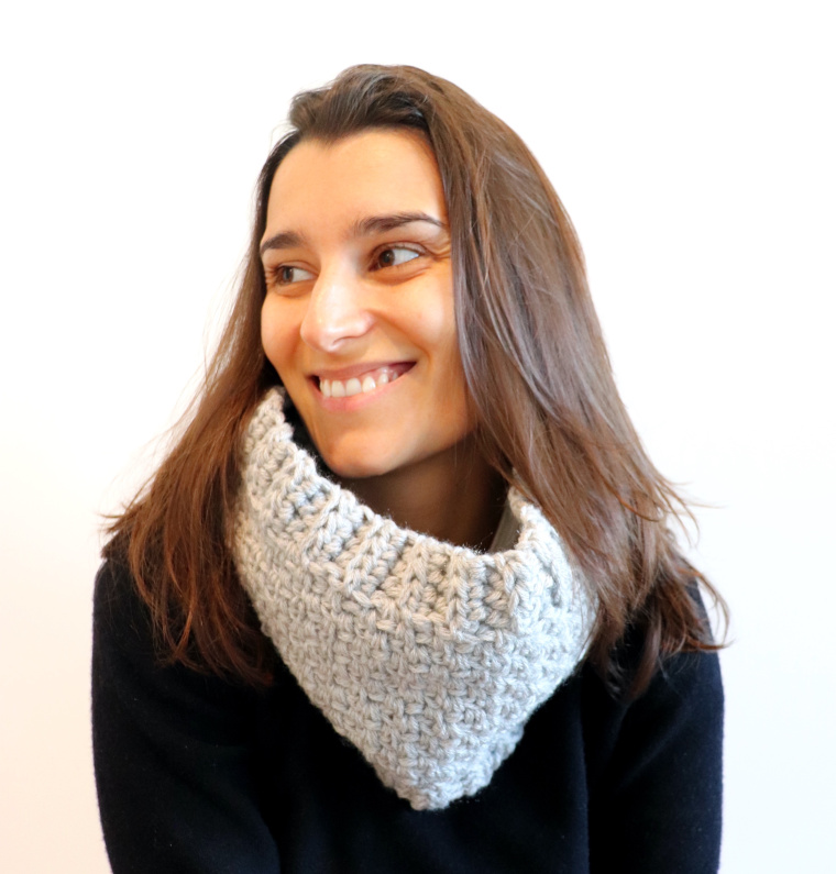 Susana of Fluffy Stitches wearing the Crochet Easy Moss Cowl in light grey and a black sweater against a white background.