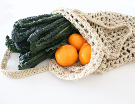 The crochet waffle market bag on a white surface with greens and vegetables coming out